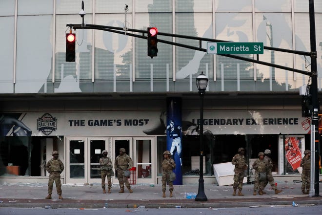 The Georgia National Guard lines up in front of the of the College Football Hall of Fame in the aftermath of a demonstration against police violence on Saturday, May 30, 2020, in Atlanta. [Brynn Anderson/The Associated Press]
