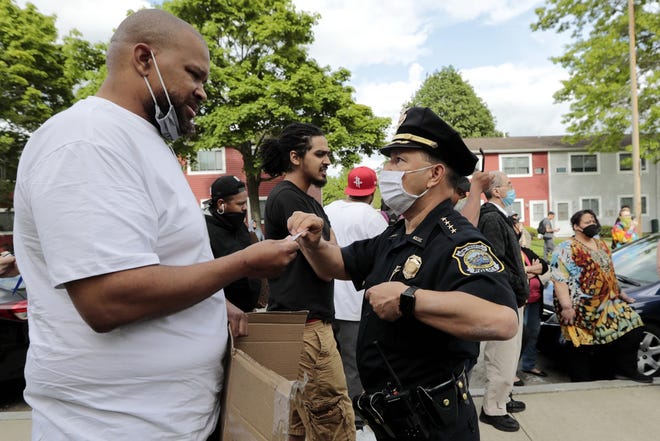 New Bedford Police Chief Joseph Cordeiro offers his card to a protestor in the hope of opening a line of communication. The protest earlier this year started at the intersection of Union Street and County Street in downtown New Bedford and progressed to the site where Malcom Gracia was killed by police on Cedar Street in 2012. [ PETER PEREIRA/THE STANDARD-TIMES/SCMG ]