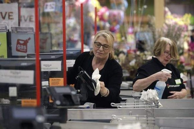 In this file photo, cashiers at the Stop & Shop in Quincy sanitize a card reader and the checkout area as a precaution out of concern about the spread of the coronavirus. [AP Photo]
