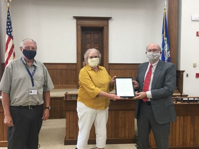 Gwen Chamberlain, former Editor of The Chronicle-Express (center), receives the Yates County Legislature’s resolution commending her work from Chairman Doug Paddock with Legislator Edward Bronson.