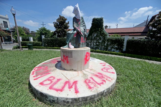 The statue of educator Sophie Bell Wright, whose father served in the Confederate Navy and Army, is covered with a white hood and spray-painted with the letters BLM on July 10 in New Orleans. The statue was one of many throughout New Orleans that protesters say celebrate white supremacy. [PHOTO BY MICHAEL DEMOCKER/GETTY IMAGES]