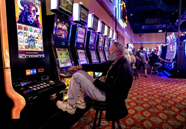 In this May 11 photo, a masked Jimmy Tearney plays the slots at the Thunderbird Casino in Norman. Some Oklahoma casinos have banned smoking due to requirements for patrons to wear masks. [Chris Landsberger/The Oklahoman]