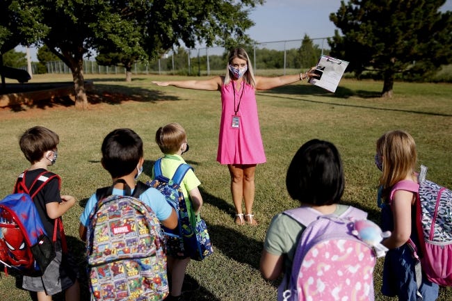 Kindergarten teacher Lindsay Giddens holds her arms out to demonstrate to her students how to stayed spaced as they arrive for their first day of school at Edmond Public Schools' Charles Haskell Elementary. Edmond Public Schools opted for a blended learning model which has students alternate between at-home learning and attending class in person. [Bryan Terry/The Oklahoman]