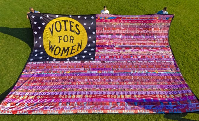 Oklahoma artist Marilyn Artus, back row center, displays her completed multi-year collaborative project "Her Flag," which commemorates the 100th annivesary of the 19th Amendment, at Scissortail Park in Oklahoma City, Okla. on Friday, Aug. 21, 2020. The completed flag will be exhibited at the Clinton Presidential Library for three weeks starting Aug. 26. [Chris Landsberger/The Oklahoman]