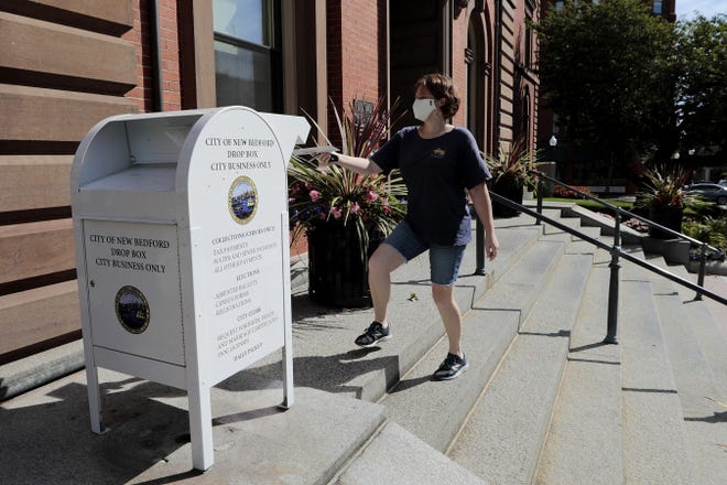 Rene Davey casts her ballot into the New Bedford official business mailbox found at the entrance to City Hall in downtown New Bedford. [ PETER PEREIRA/THE STANDARD-TIMES/SCMG ]