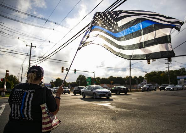 Nancy Delsignore waves a thin blue line flag at the We Back the Blue rally organized by the Middleborough Republican Town Committee at the intersection of Route 28 and Route 105 in Middleboro on Monday, Sept. 28, 2020. [Alyssa Stone/The Enterprise]
