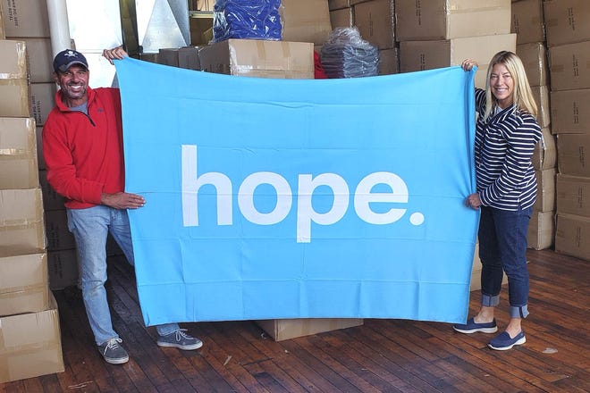 Peter and Dede Moubayed, owners of NorthEast Fleece in Fall River, proudly hold their latest Fleece for Peace blanket designed for charitable giving. NorthEast will match the gift and provide free shipping to the customer's charity of choice. [Courtesy photo]