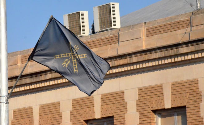 The winning flag in a contest to create an official flag for the city of Newton waves Friday along Main Street in black, yellow and white designs. [CHAD FREY/Newton Kansan]