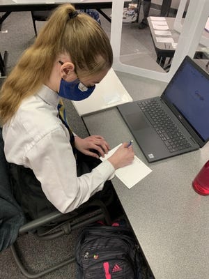 Alyia Johansing writes a thank you note to Mercy Health medical professionals as part of a special National Catholic School Week project at Cristo Rey Oklahoma City Catholic High School. [Photo provided]
