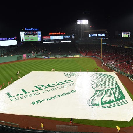 The Boston Red Sox grounds crew puts the tarp on the field during the fourth inning against the New York Mets at Fenway Park.
