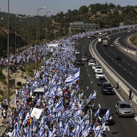 July 22, 2023: Demonstrators wave Israeli national flags as they march on the highway near the town of Mevasseret Zion, during a multi-day march from Tel Aviv to Jerusalem to protest the government's judicial overhaul bill ahead of a vote in the parliament. Israel has been rocked by a months-long wave of protests after the government unveiled in January plans to overhaul the judicial system that opponents say threatens the country's democracy.