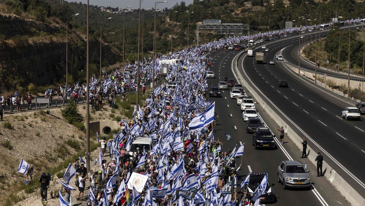 July 22, 2023: Demonstrators wave Israeli national flags as they march on the highway near the town of Mevasseret Zion, during a multi-day march from Tel Aviv to Jerusalem to protest the government's judicial overhaul bill ahead of a vote in the parliament. Israel has been rocked by a months-long wave of protests after the government unveiled in January plans to overhaul the judicial system that opponents say threatens the country's democracy.
