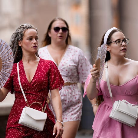Tourists use foldable fans to cool off as they visit Rome, Saturday, July 22, 2023. An intense heat wave has reached Italy, bringing temperatures close to 40 degrees Celsius in many cities across the country.