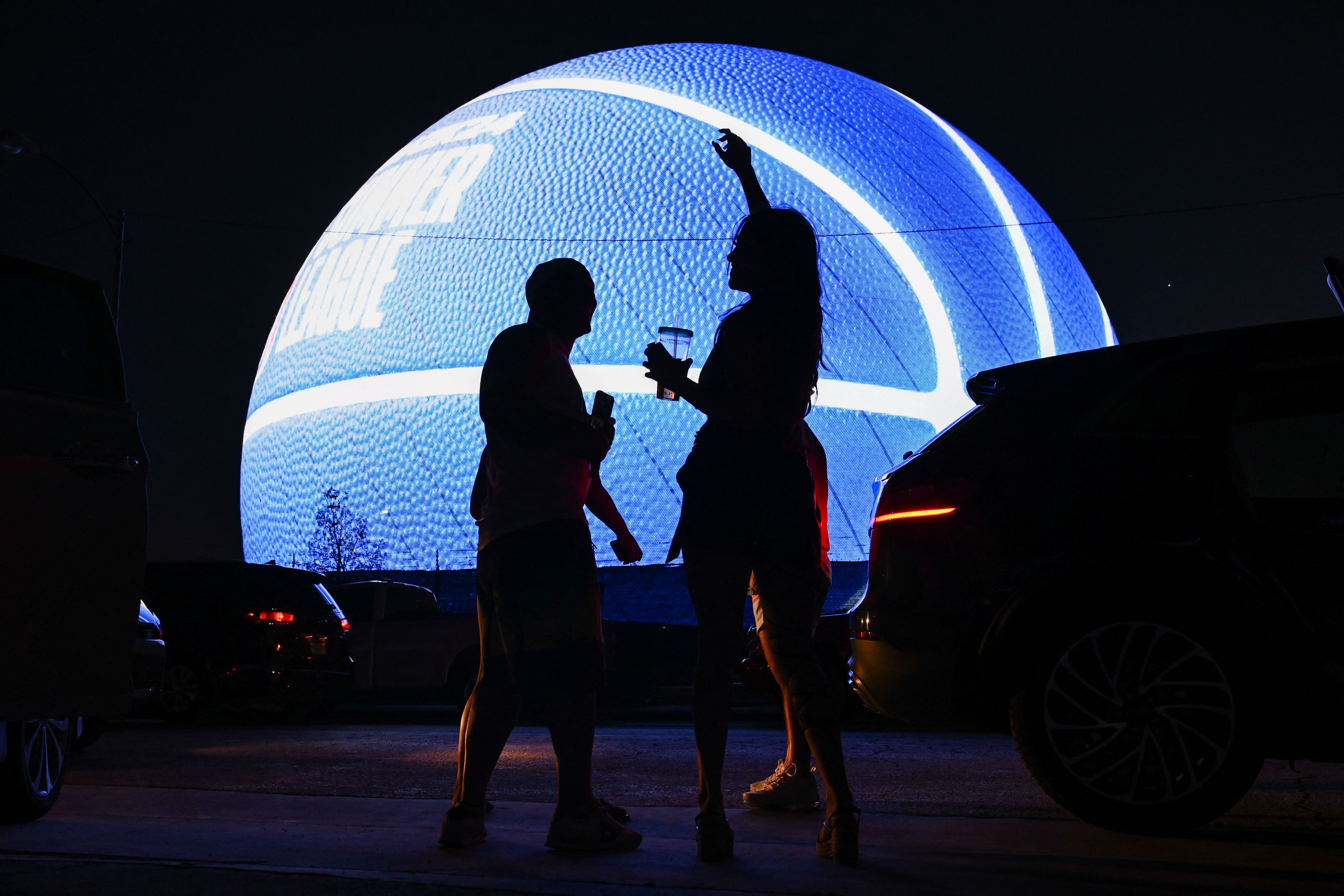 People dance while viewing the MSG (Madison Square Garden) Sphere, a new music entertainment arena, as it is lit up as a basketball to celebrate the 2023 NBA Summer League in Las Vegas, Nevada, on July 9, 2023.