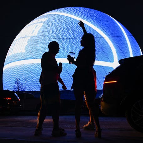 People dance while viewing the MSG (Madison Square Garden) Sphere, a new music entertainment arena, as it is lit up as a basketball to celebrate the 2023 NBA Summer League in Las Vegas, Nevada, on July 9, 2023.