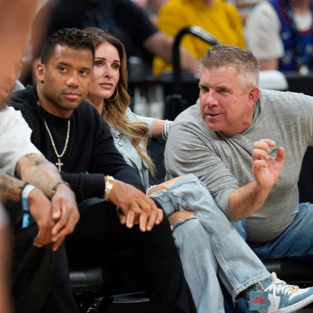 Denver Broncos head coach Sean Payton, right, chats with quarterback Russell Wilson, left, as Payton's wife, Skylene, looks on from courtside seats in the first half of Game 5 of an NBA basketball semifinal playoff series between the Phoenix Suns and Denver Nuggets Tuesday, May 9, 2023, in Denver.