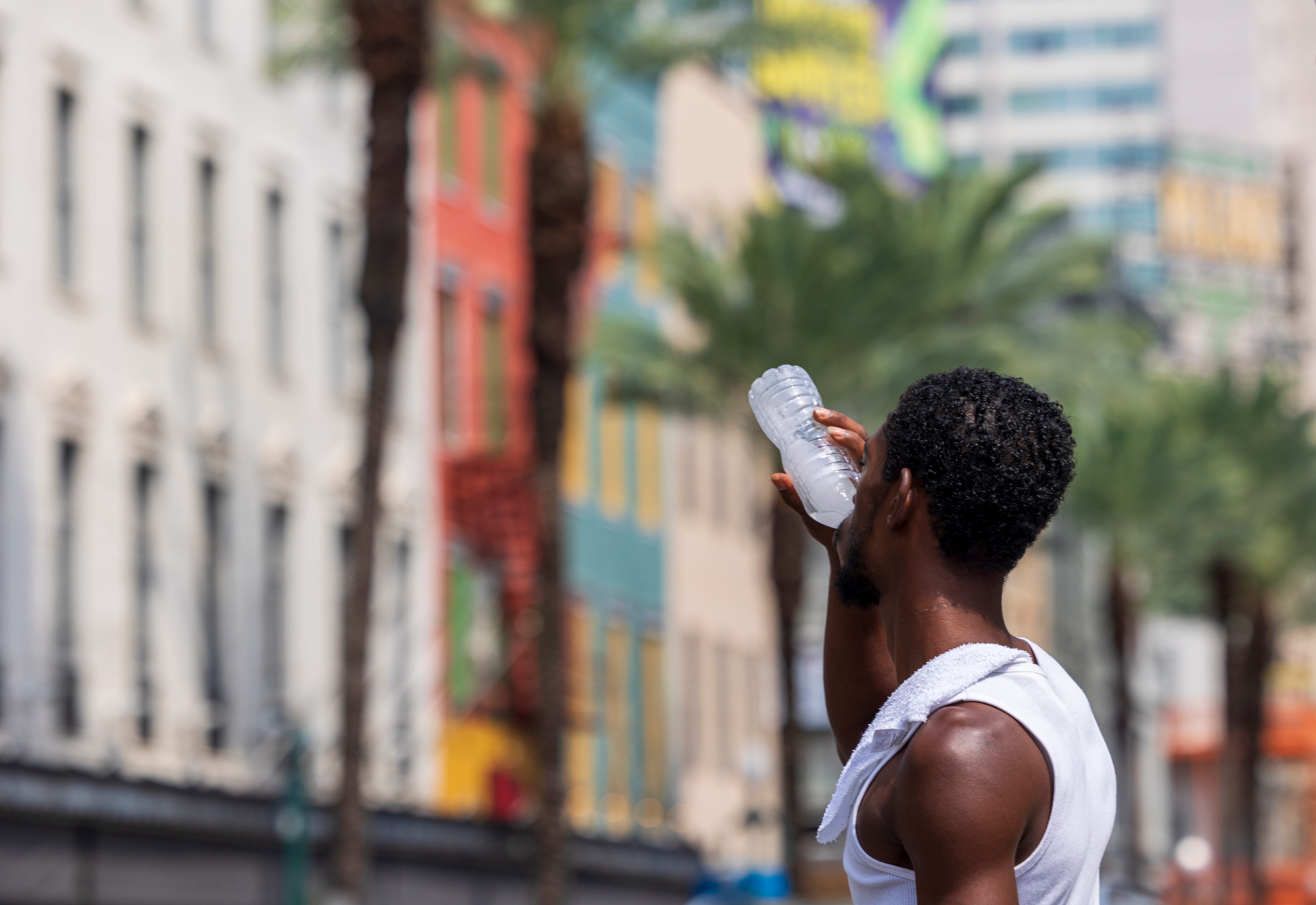 A person drinks water to stay hydrated at the corner of Canal and Bourbon streets near the French Quarter during a record heatwave in New Orleans on Monday, July 31, 2023.