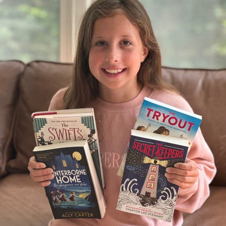 Ten-year-old Harper poses with her Mystery Box book selections curated by "The Novel Neighbor."