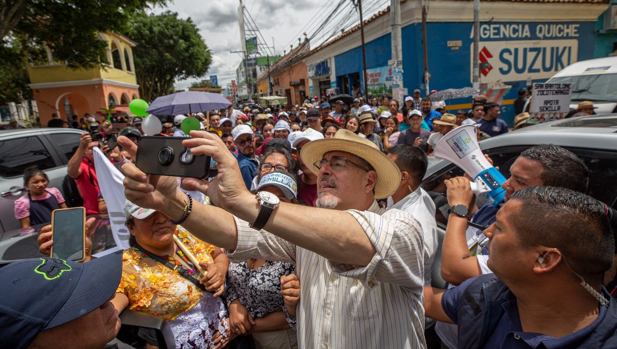Presidential candidate Bernardo Arevalo takes selfies with his supporters in the central square of Santa Cruz del Quiche, Guatemala on Aug.11, 2023, after a political rally.