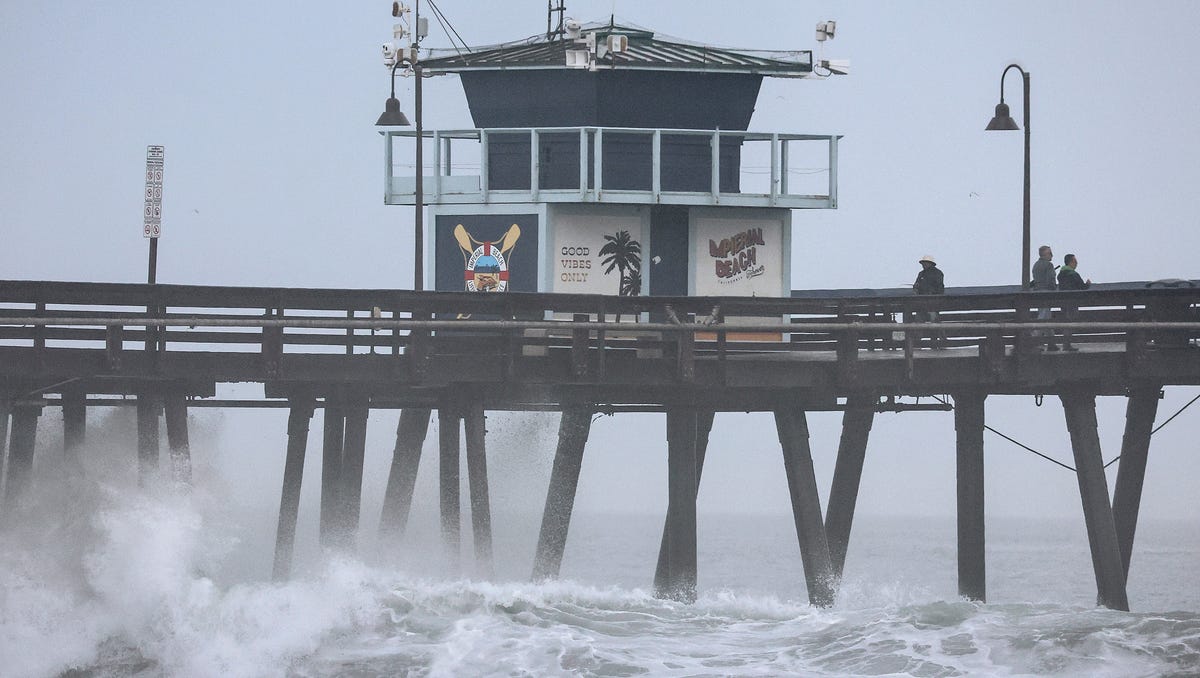 People stand on a pier over the Pacific Ocean with Tropical Storm Hilary approaching in San Diego County on August 20, 2023 in Imperial Beach, California. Southern California is under a first-ever tropical storm warning as Hilary approaches with parts of California, Arizona, and Nevada preparing for flooding and heavy rains. All California state beaches have been closed in San Diego and Orange counties in preparation for the impacts from the storm which was   downgraded from hurricane status.