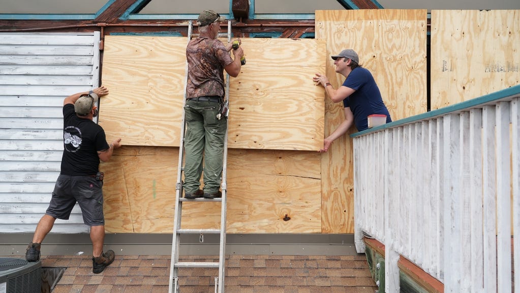 (from left) Chris Laite, Clay Brooks and Jordan Keeton, owner of the restaurant '83 West' board up the building before the storm on Aug. 29, 2023. The Gulf Coast of Florida prepares for the arrival of Hurricane Idalia. The fast-moving storm is forecast to make landfall on Wednesday, according to the latest advisory from the National Hurricane Center.