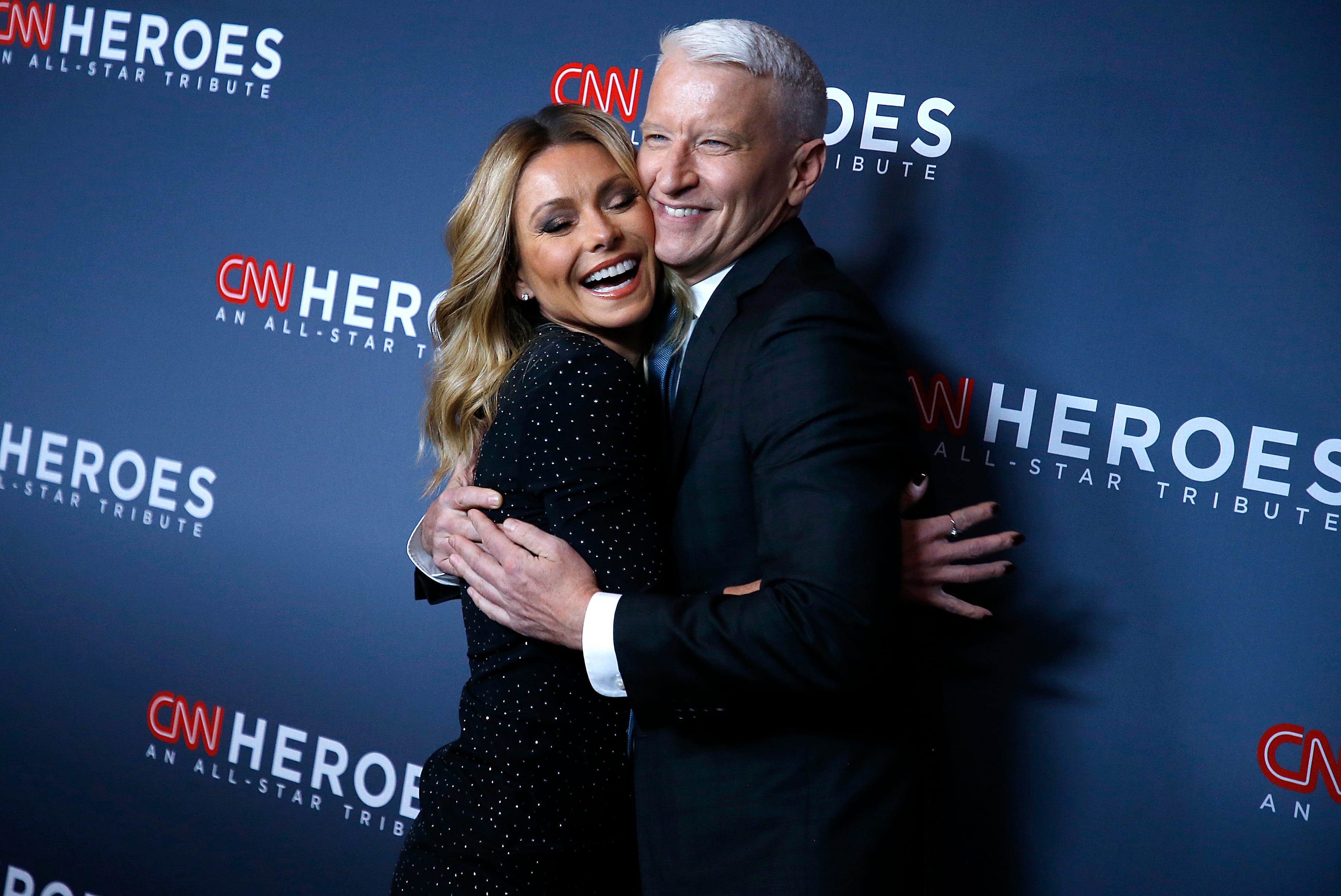 Anderson Cooper (right) recalled a "truly mortifying" experience at a Madonna concert in Brooklyn, New York, on Kelly Ripa's (left) "Let's Talk Off Camera with Kelly Ripa" podcast.