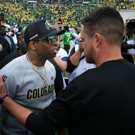 Colorado coach Deion Sanders, left, and Oregon's Dan Lanning meet at midfield after the game at Autzen Stadium.