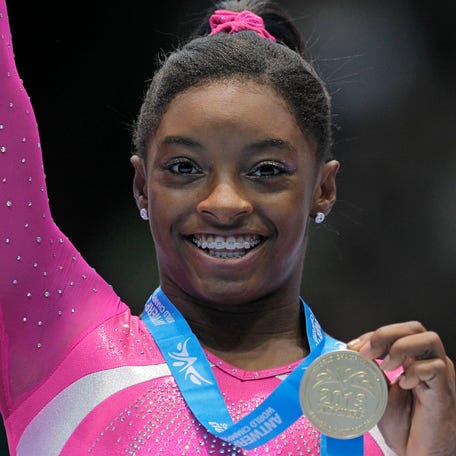 Simone Biles shows her gold medal after the all-around final at the World Championships in Antwerp, Belgium, on Oct. 4, 2013.