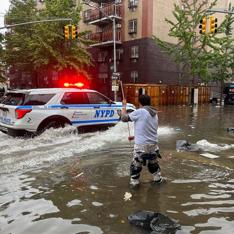 A man works to clear a drain in flood waters, Friday, Sept. 29, 2023, in the Brooklyn borough of New York. A potent rush-hour rainstorm has swamped the New York metropolitan area. The deluge Friday shut down swaths of the subway system, flooded some streets and highways, and cut off access to at least one terminal at LaGuardia Airport.