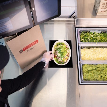 A crew member takes a bowl created by the new automated "digital makeline" being tested at the Chipotle Cultivate Center innovation hub in Irvine, California.