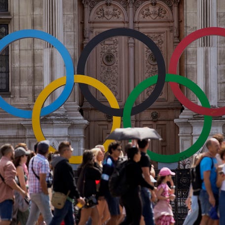 A group of tourists walk past the Olympic rings in front of the Paris City Hall one year until the Paris 2024 Olympic Games opening ceremony, Wednesday, July 26, 2023.
