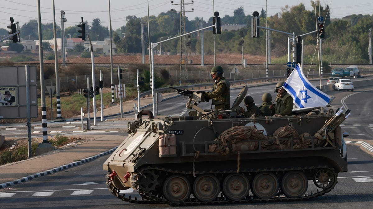 Israeli forces cross a main road in their armoured personnel carrier (APC) as additional troops are deployed near the southern city of Sderot on October 8, 2023. Israeli Prime Minister Benjamin Netanyahu has warned of a "long and difficult" war, as fighting with Hamas left hundreds dead on both sides after a surprise attack on Israel by the Palestinian militant group on October 7.