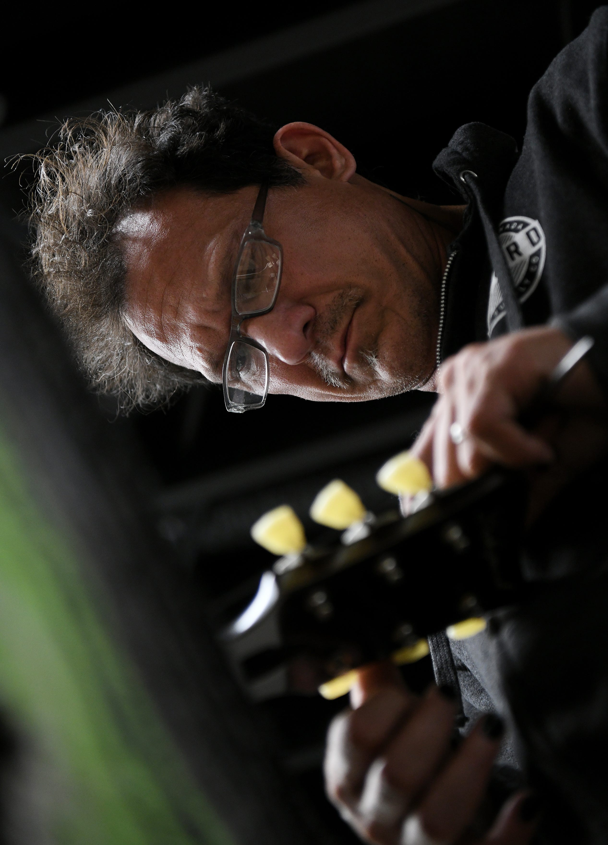 Gabriel Currie works on the tuning keys on a guitar at Echopark Guitars in Detroit on June 7, 2023. 
(Robin Buckson / The Detroit News)