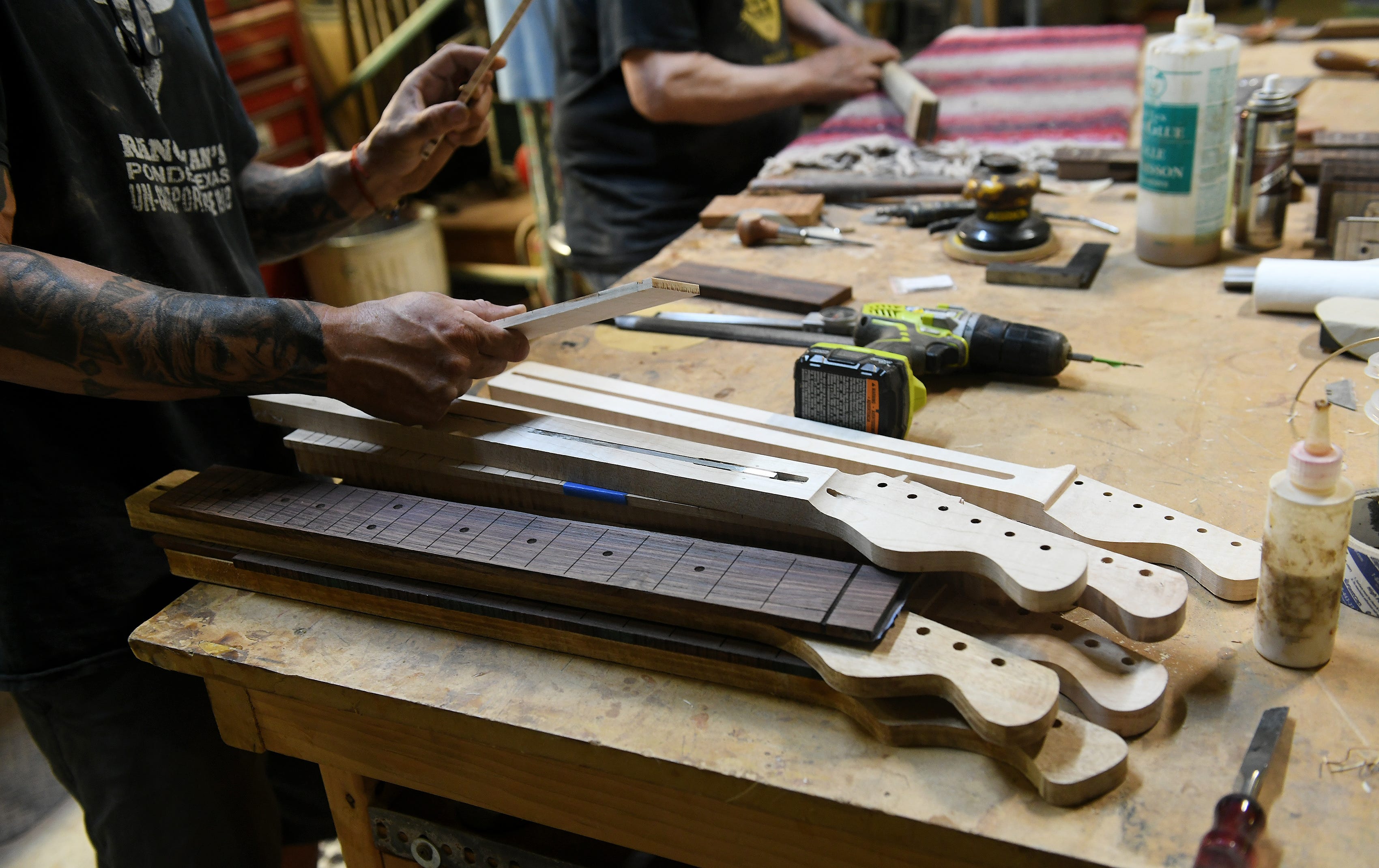 Echopark founder Gabriel Currie looks at guitar necks made from different types of wood at Echopark Guitars in Detroit on July 21, 2023.