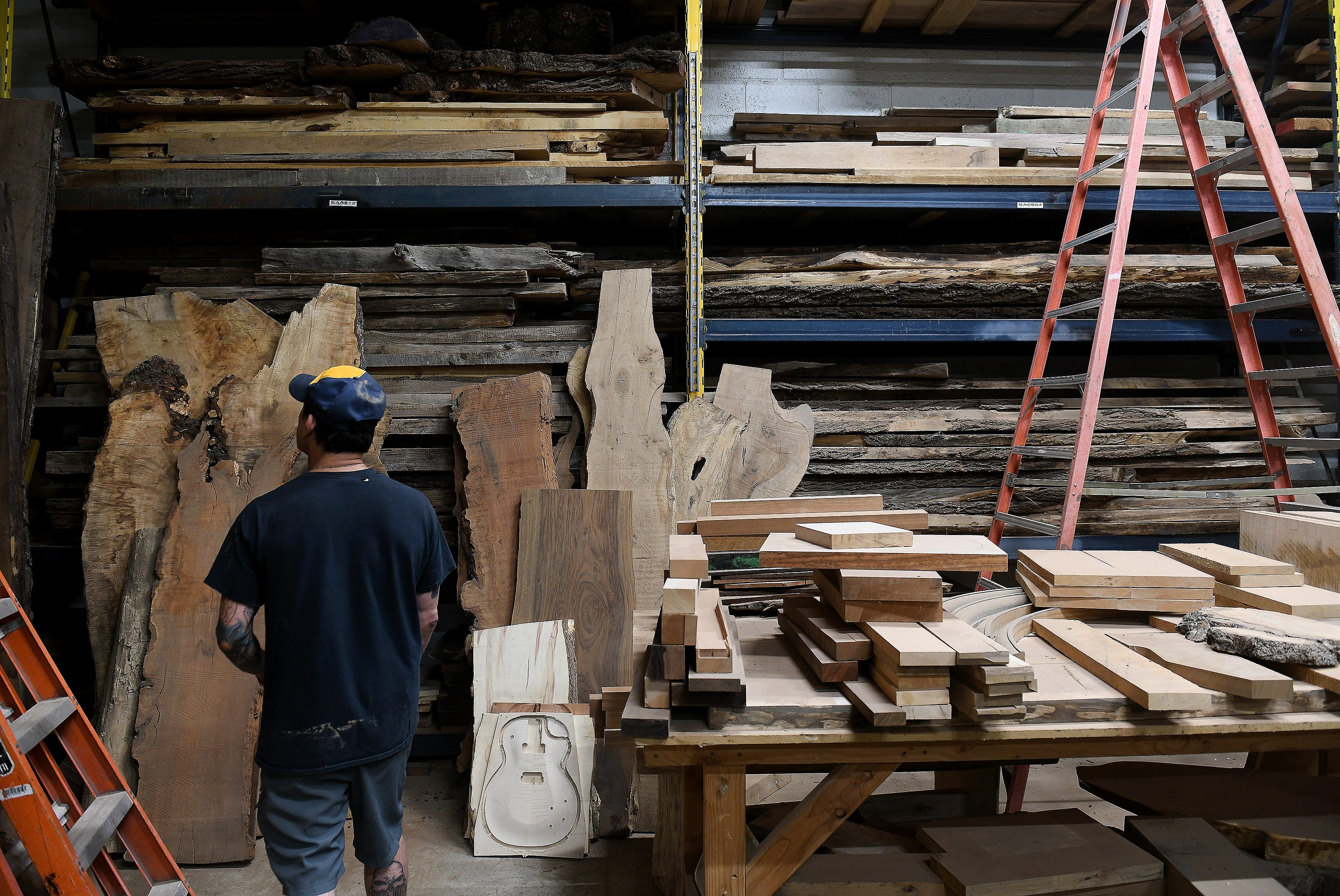 Gabriel Currie looks over some of the wood on the shelves in his Echopark Guitars headquarters in Detroit on July 21, 2023.