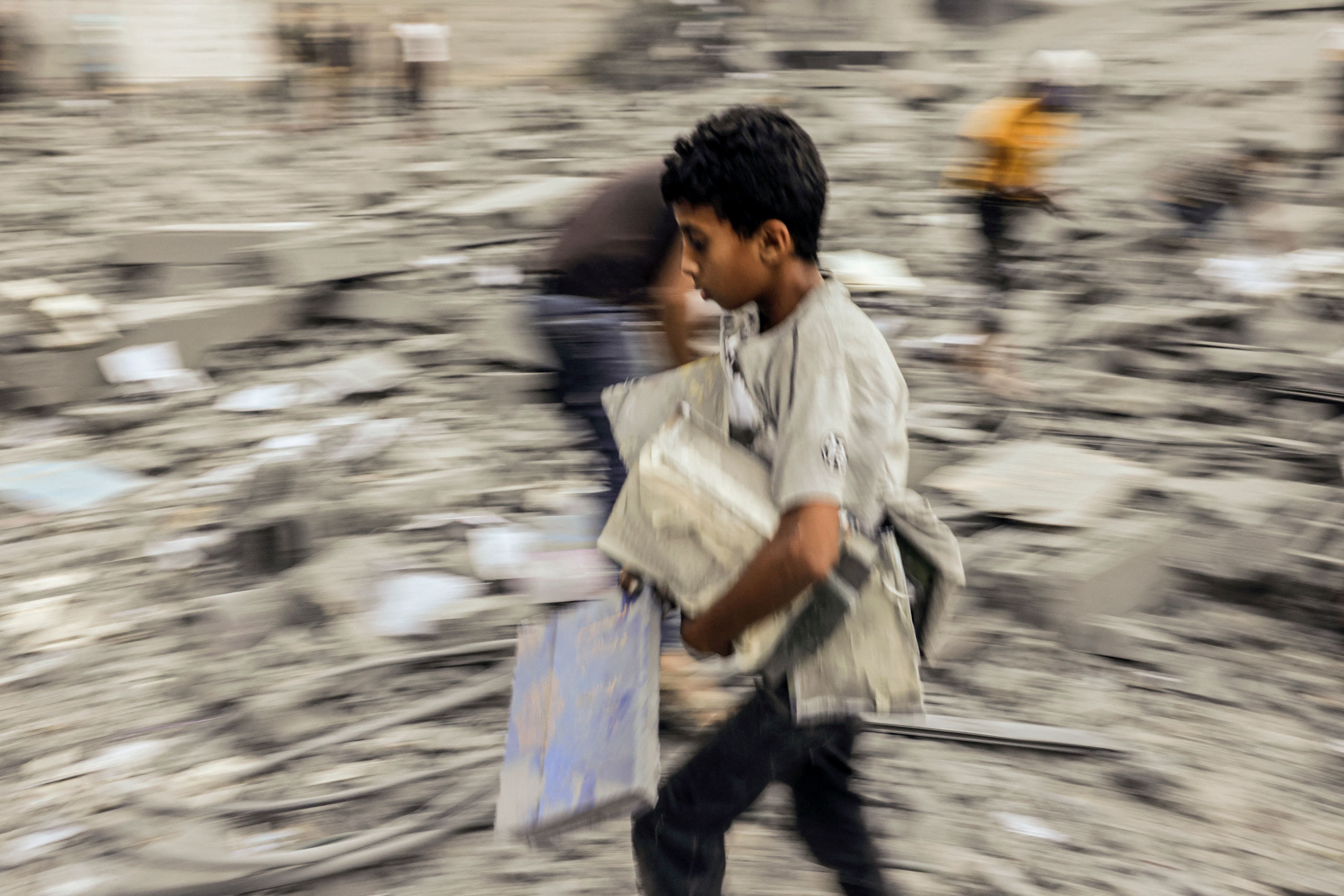 October 15, 2023: A child walks away with belongings salvaged from the rubble of a building hit in an Israeli strike on Rafah in the southern Gaza Strip on October 15, 2023. Israel embarked on a withering air campaign against Hamas militants in Gaza after they carried out a brutal attack on Israel on October 7 that left more than 1,400 people killed in Israel.