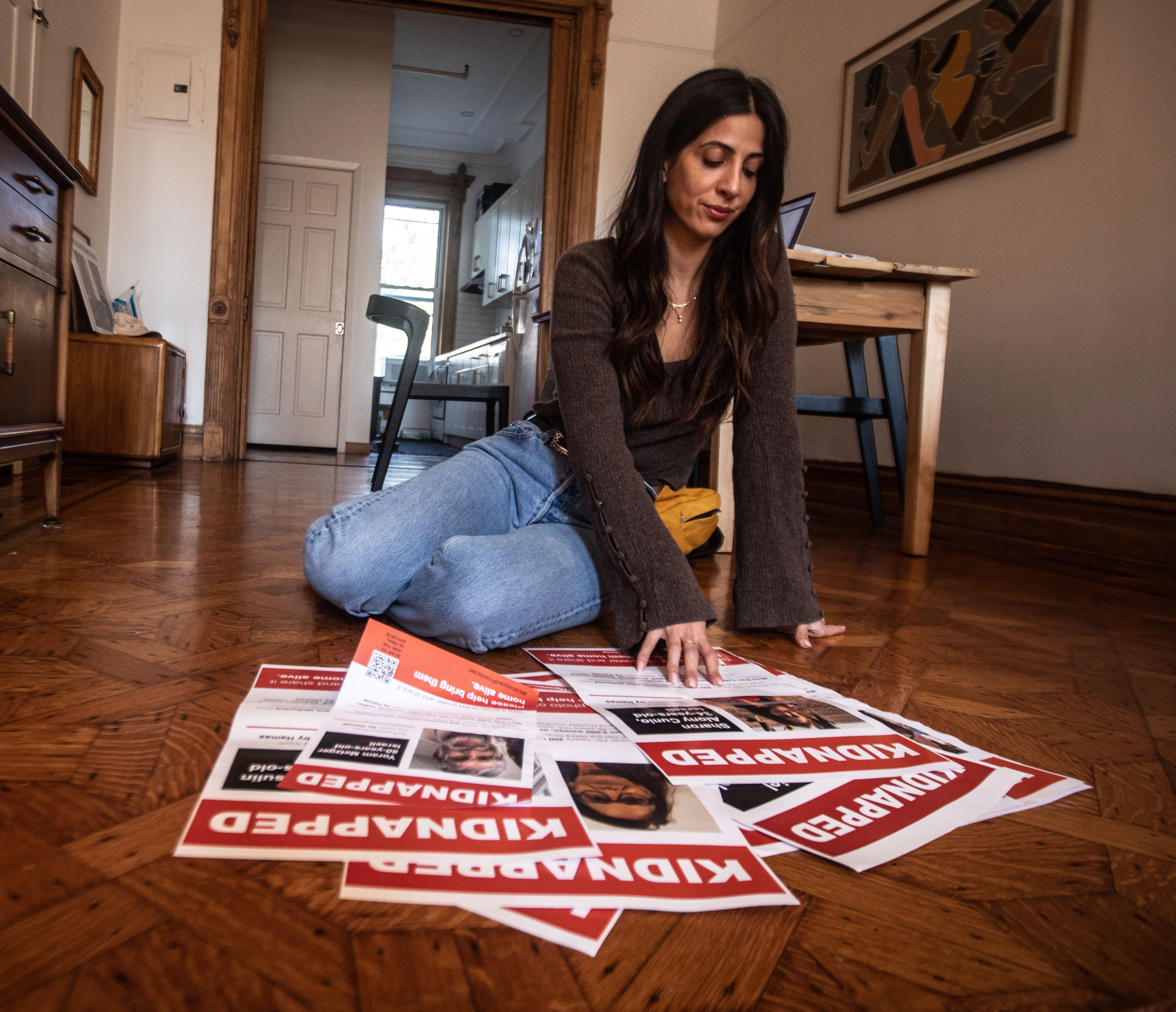 Alana Zeitchik, 38, looks at a poster of one her cousins who is being held captive by Hamas in the Gaza Strip. Zeitchik, photographed in her Brooklyn apartment Oct. 19, 2023, has six cousins that are currently being held by Hamas. "I'm just a person that loves my family very deeply, and I have to advocate for them" she say, "I can't envision sitting here doing nothing."