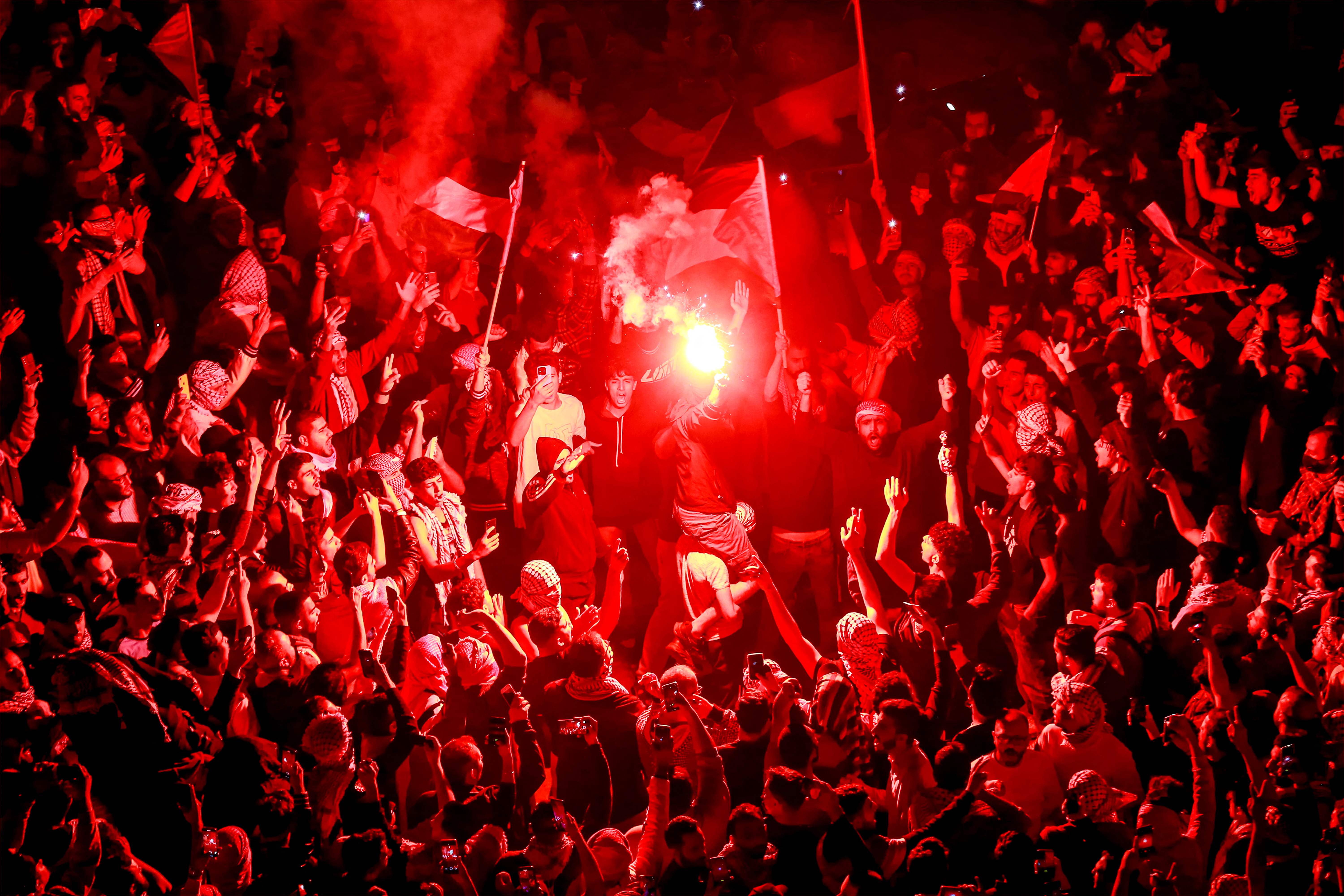A demonstrator lights up a flare as others gather outside the Israeli embassy headquarters in Amman late on Oct. 18, 2023, to show solidarity with the Palestinians of the Gaza Strip. Thousands rallied across the Arab and Muslim world on Oct. 18 to protest the deaths of hundreds of people in a strike on a Gaza hospital that they blame on Israel, despite its denials.