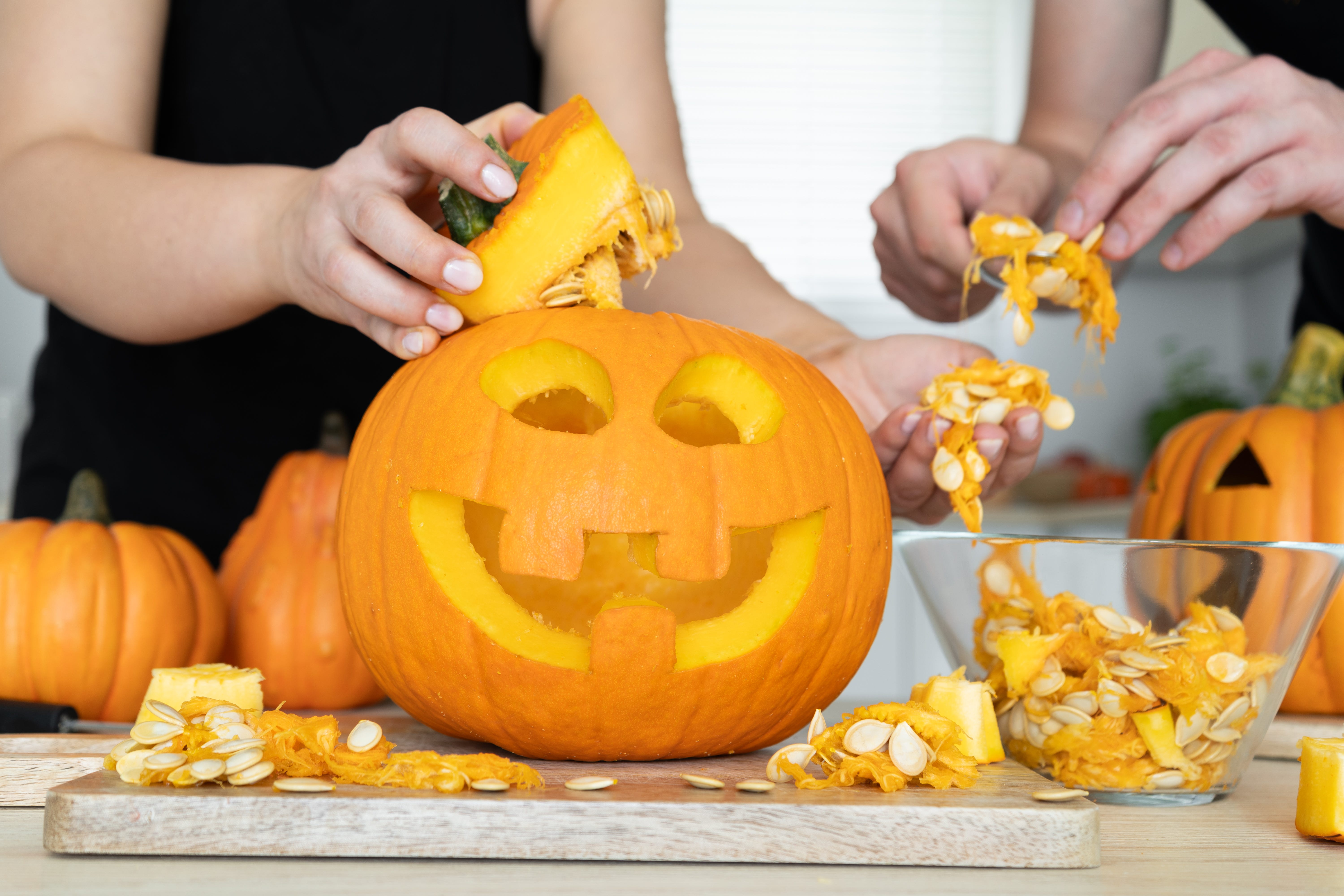 A man and woman hands gutting Halloween pumpkin.