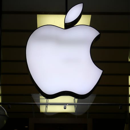 The Apple logo is illuminated at a store in the city center of Munich, Germany on Dec. 16, 2020.