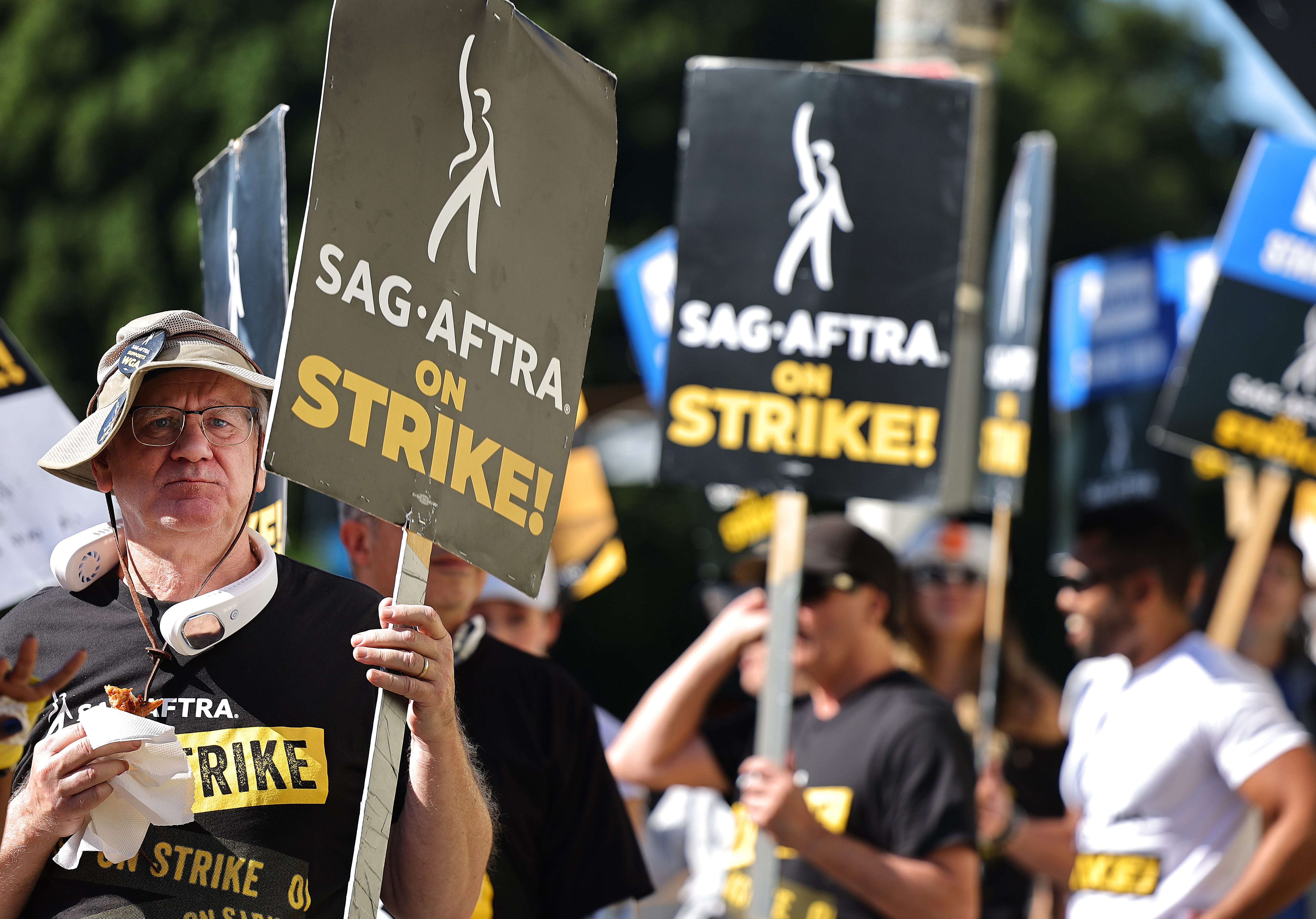 A picketer eats donated free pizza for strikers as SAG-AFTRA members and supporters picket outside Paramount Studios on day 113 of their strike against the Hollywood studios on Nov. 3, 2023, in Los Angeles, California. Contract negotiations between the actors union and the Alliance of Motion Picture and Television Producers (AMPTP) continue in the strike, which began on July 14.