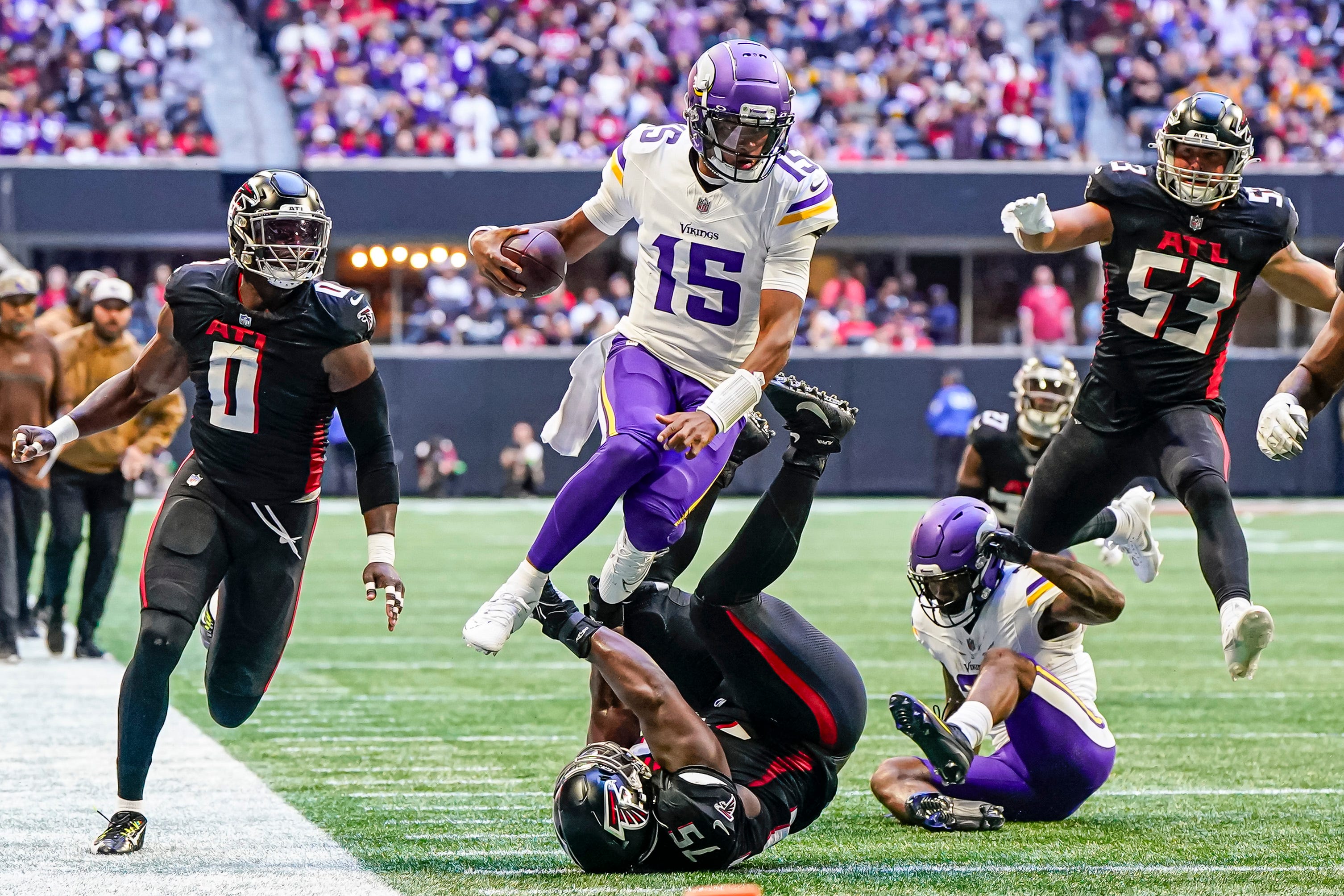 Minnesota Vikings quarterback Joshua Dobbs (15) jumps over Atlanta Falcons defensive tackle Kentavius Street (75) during the second half at Mercedes-Benz Stadium.