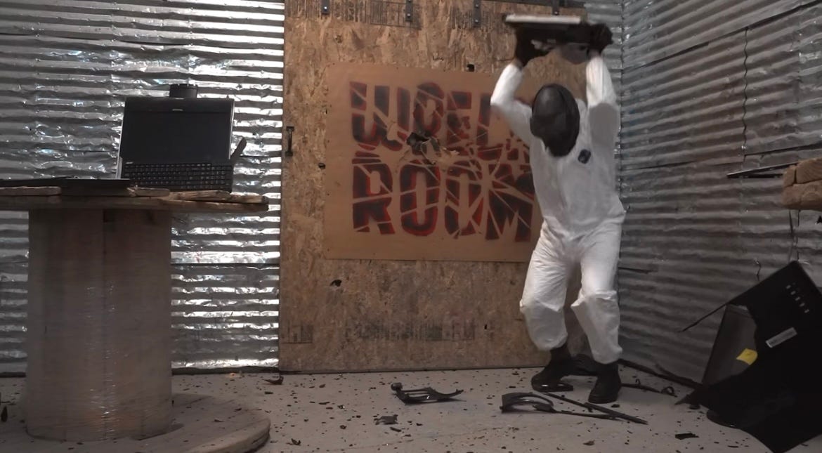 A person inside Wreck Room Las Vegas destroying items while wearing protective gear.