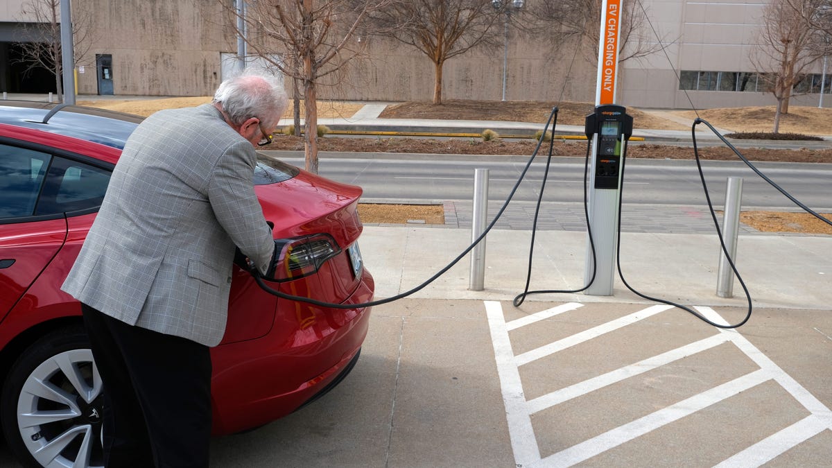 Jim Holman plugs in his Tesla Model 3 on March 4, 2022, at the EV charging station in the Santa Fe Station parking lot on E.K. Gaylord Boulevard.