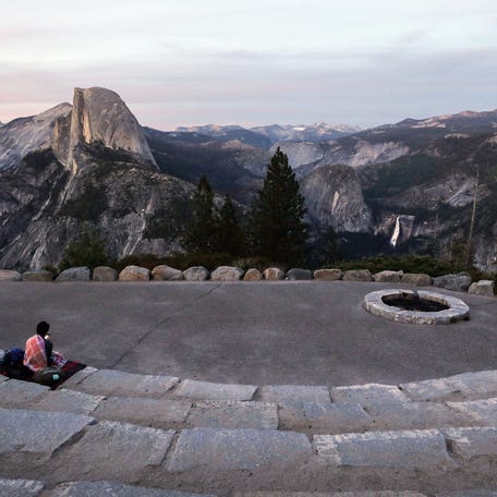 2023 National Park Tab — YOSEMITE NTL PARK, CALIFORNIA - JUNE 18: Dusk falls over Half Dome (CENTER L) and Nevada Fall (CENTER R) as a visitor sits, on June 18, 2020, in Yosemite National Park, California.         Photo by Mario Tama/Getty Images ORG XMIT: 775521961 [Via MerlinFTP Drop]
