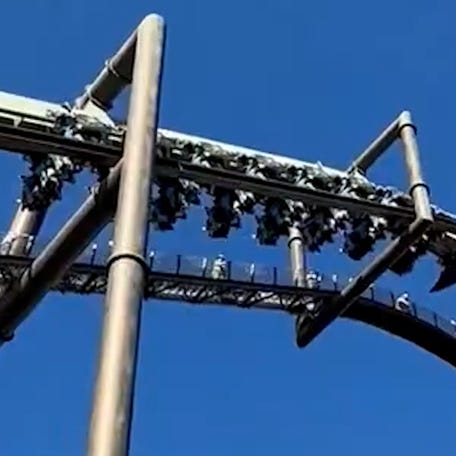 Patrons of Universal Studios Japan hangs from a roller coaster after the ride's safety system engaged midair.