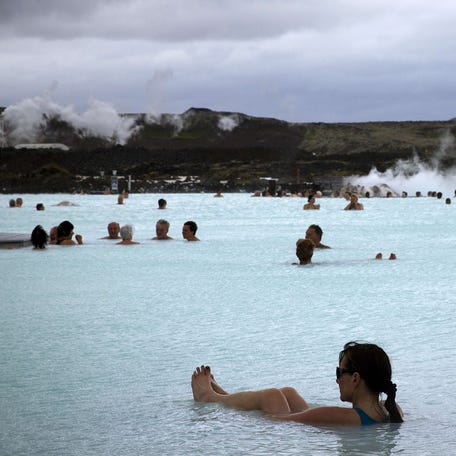 People bathe in the "Blue Lagoon" geothermal spa, one of the most visited attractions in Iceland in the Reykjanes Peninsula, Southwestern Iceland on July 5, 2014. The spa is located on a lava field.