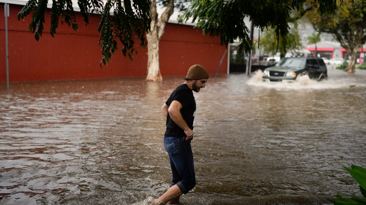 A man walks along a flooded street during a rain storm, Thursday, Dec. 21, 2023, in Santa Barbara, Calif.