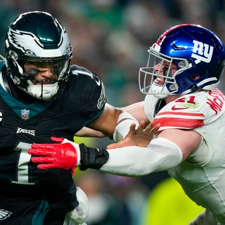 Philadelphia Eagles quarterback Jalen Hurts pushes off New York Giants linebacker Micah McFadden during the first half of an NFL football game Monday, Dec. 25, 2023, in Philadelphia.