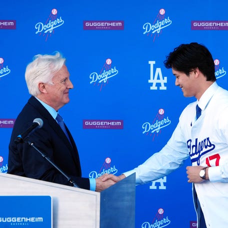 Los Angeles Dodgers player Shohei Ohtani shakes hands with Dodgers owner Mark Walter at an introductory press conference at Dodger Stadium.